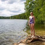 A woman in a swimming costume standing next to a lake