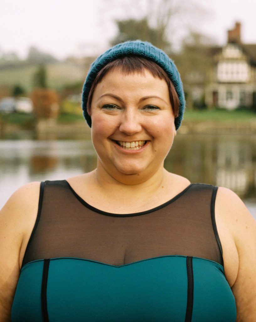 Ella Foote in swimming costume and woolly hat, with a river in the background.