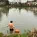A man in jammers getting into a river, back to the camera