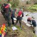 Some people collecting invertebrate samples next to a river