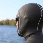 Swimmer in neoprene balaclava looking at a lake