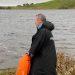 A man in a Dryrobe standing next to a lake