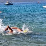 Two swimmers, shoulder to shoulder, finishing a race in the sea, heading towards the camera.