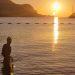 A woman standing waist deep in the sea looking at the sun rise.